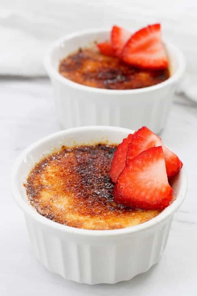 crème brûlée topped  with strawberries in white ramekins