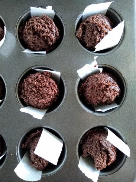 Brownie batter scooped into the muffin tin.