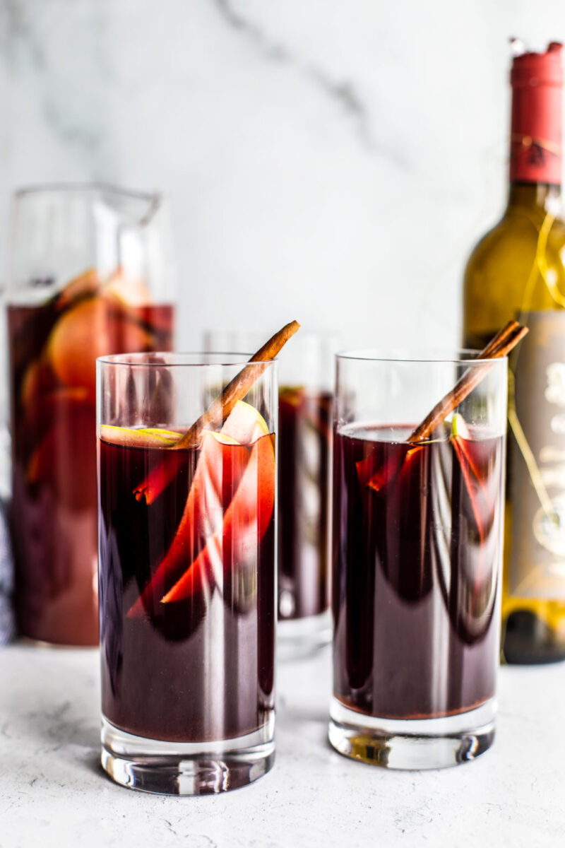 caramel red apple sangria with cinnamon barks in tall glasses