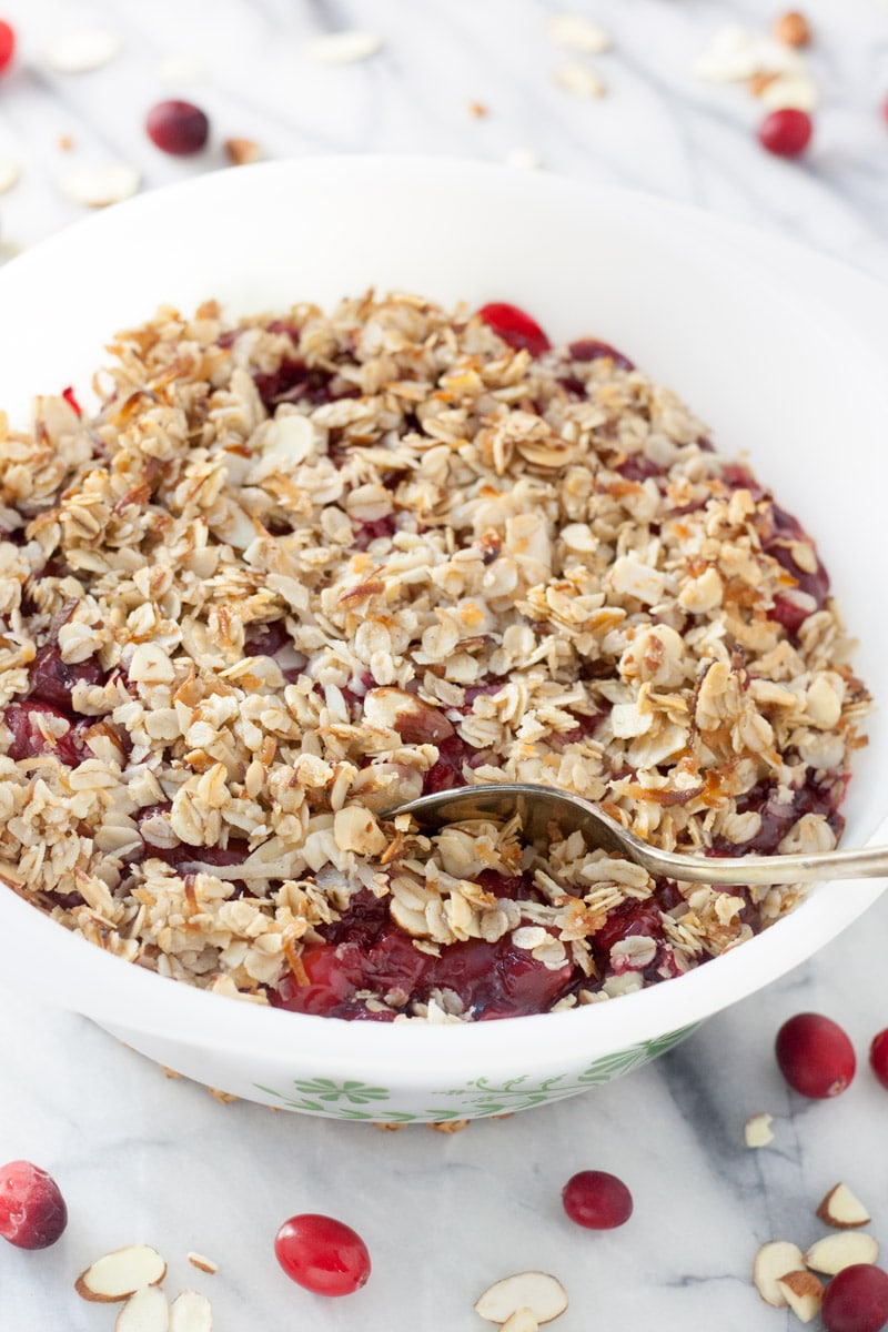 cranberry oat crisp in a white bowl with spoon