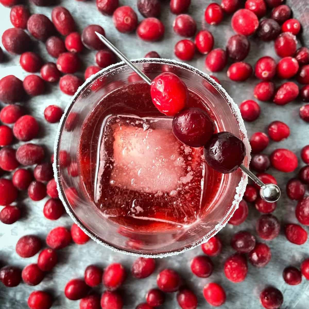 airshot image of cranberry cocktail with  one big ice in a glass and many cranberries sorrounding it