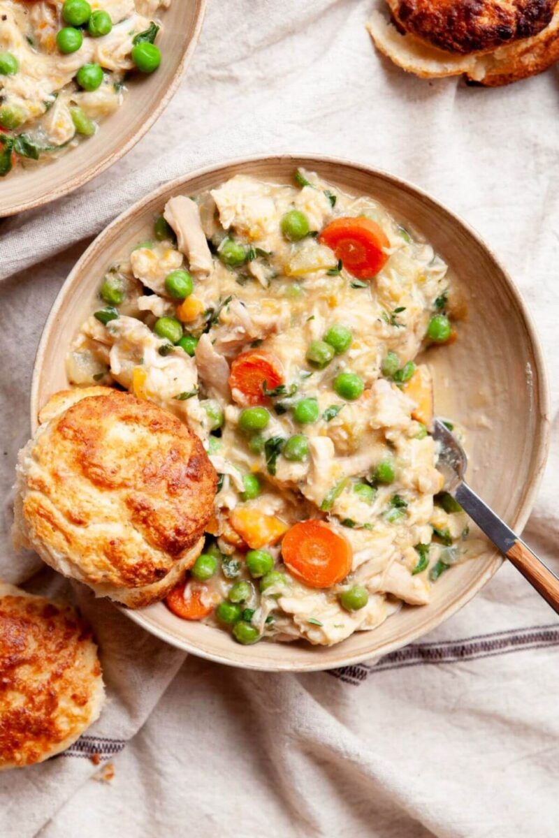 creamy crustless chicken pot pie with carrots and green peas on a white serving plate, with bread on the side