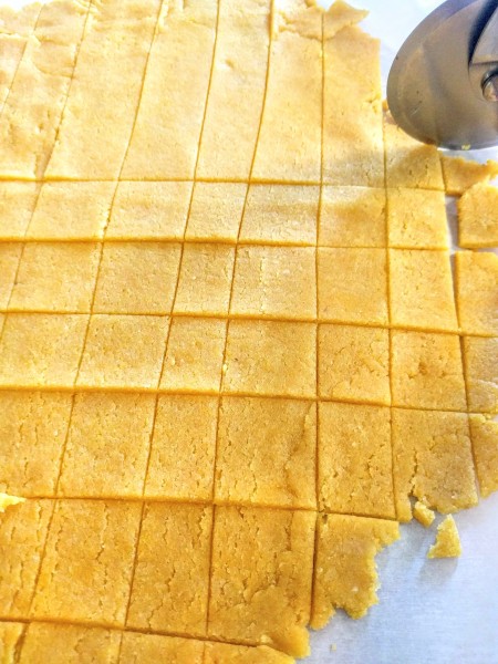 Cutting the dough into crackers with a pizza cutter.