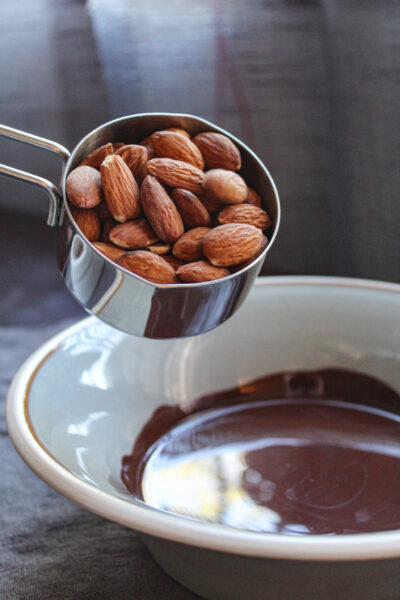 adding almonds to melted chocolate in bowl