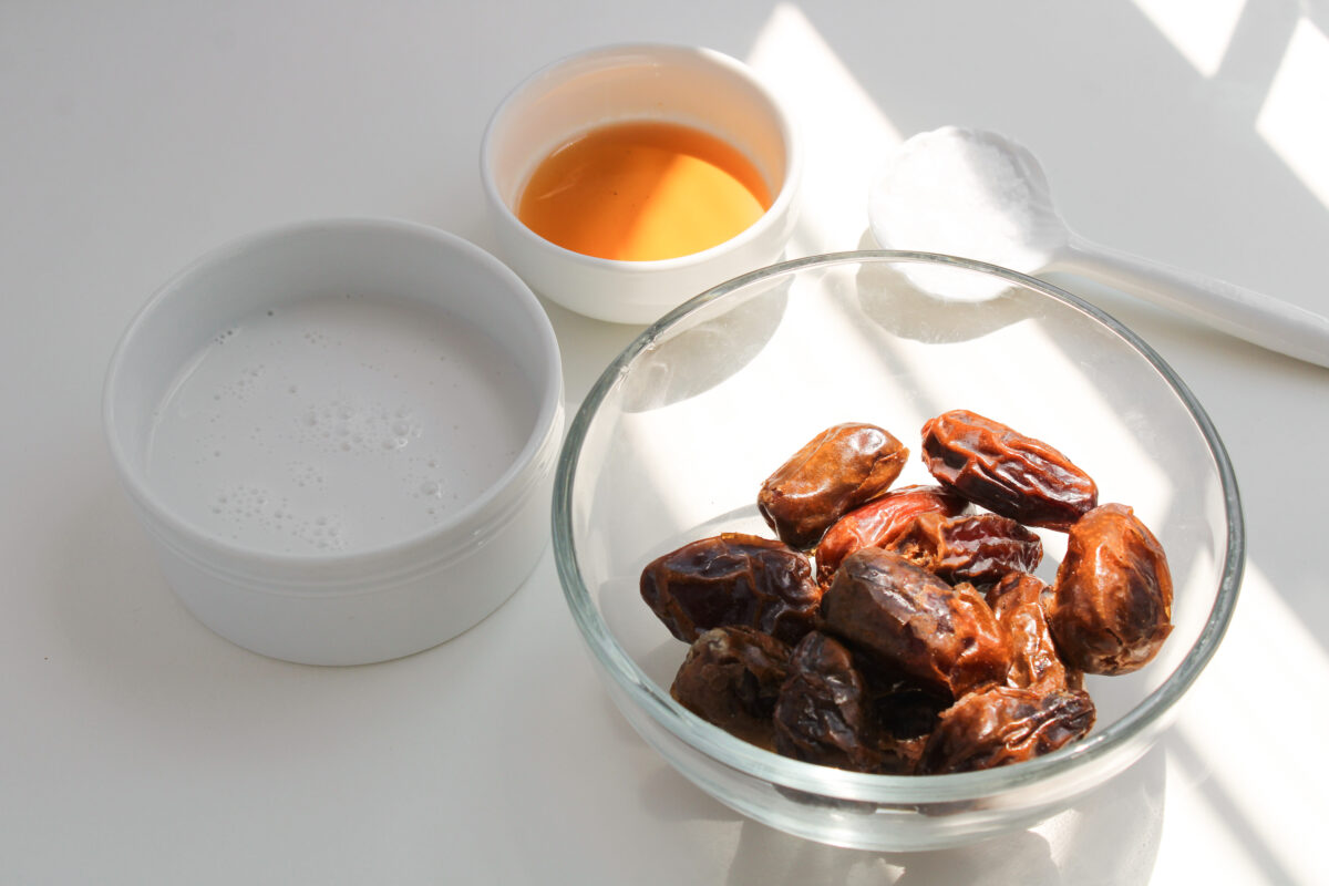 Ingredients for date caramel in individual bowls on white background.