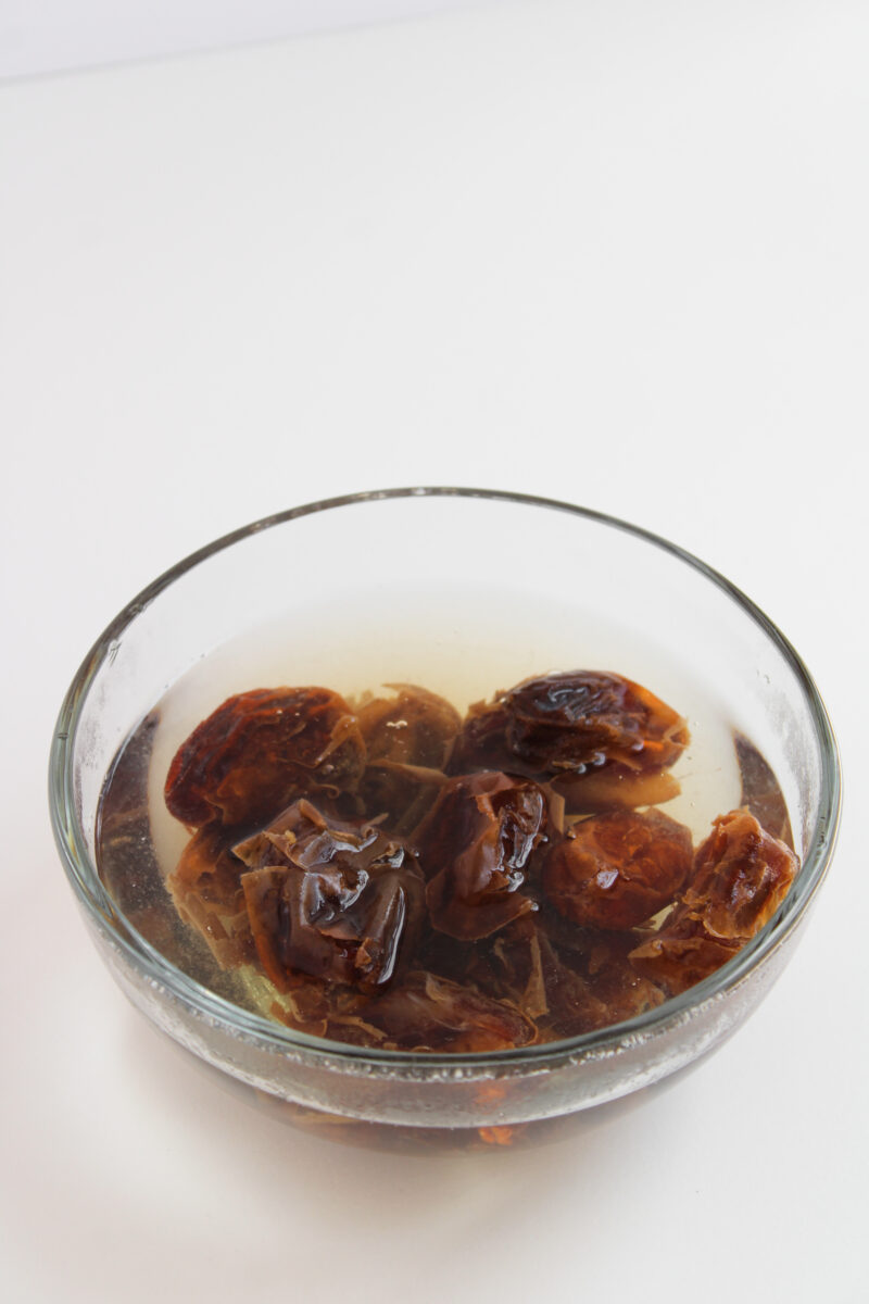 Dates soaking in water in clear bowl.