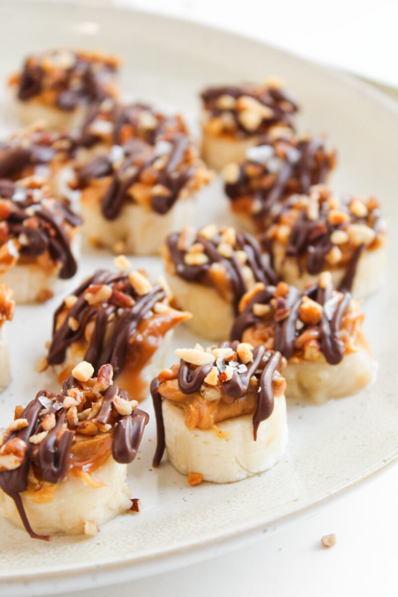 Banana snickers bites arranged on the edge of sandy color plate.