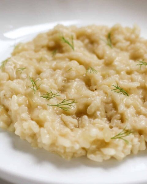 creamy cooke rice topped with fennel on a white plate