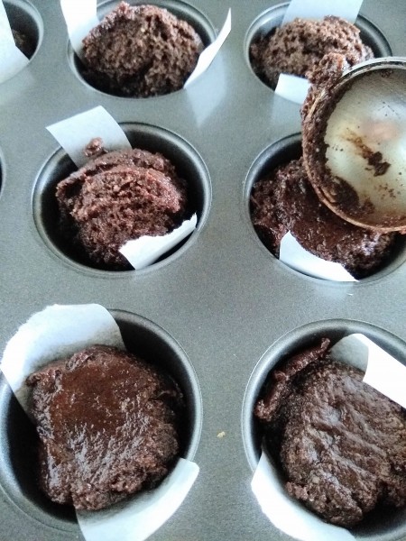 Flattening the brownie batter in the mini muffin tin.