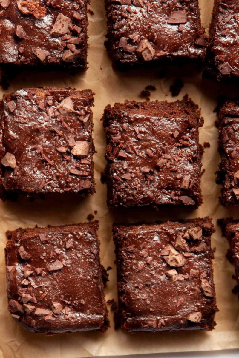 flourless brownies topped with chopped chocolates on a brown parchment paper