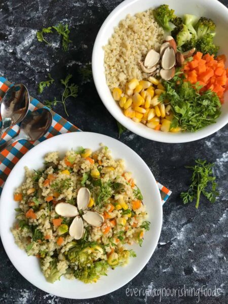 salad made with millet and veggies and herbs drizzled with dressing and topped with almonds on a white plate