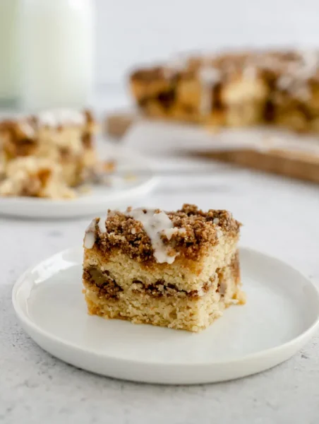 a slice of baked gluten Free Coffee Cake tpped and filled with a cinnamon streusel on a white saucer plate