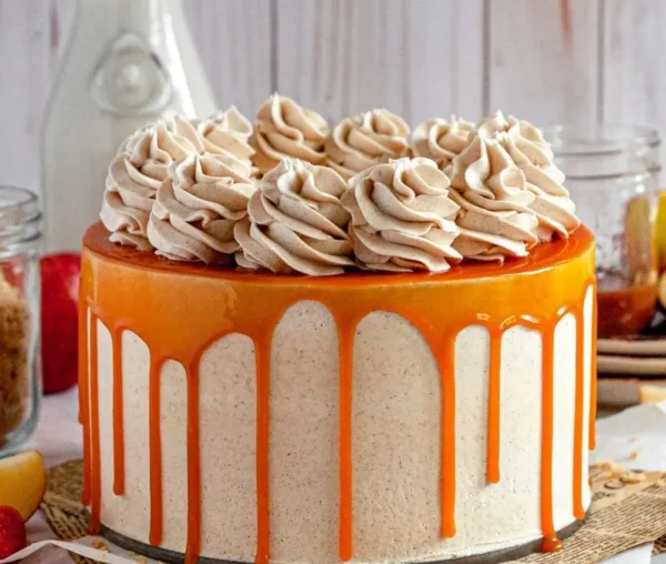 a beautiful gluten-free apple cake  stacked high with whipped salted caramel buttercream topped with caramel sauce golden drip and buttercream swirls frosting 