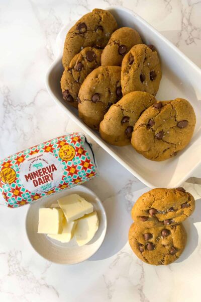 gluten free pumpkin chocolate chip cookies sprinkled with flaky seasalt in a rectangular white serving bowl with butter and additional cookies outside 