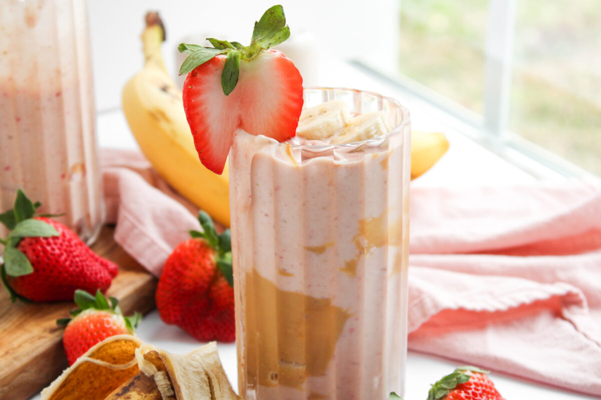 PB&J Smoothie in a class cup with pink napkin and window in the background.