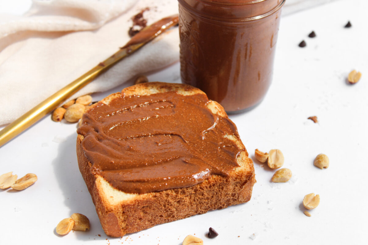 Chocolate peanut butter on toast with a jar and butter knife in the background