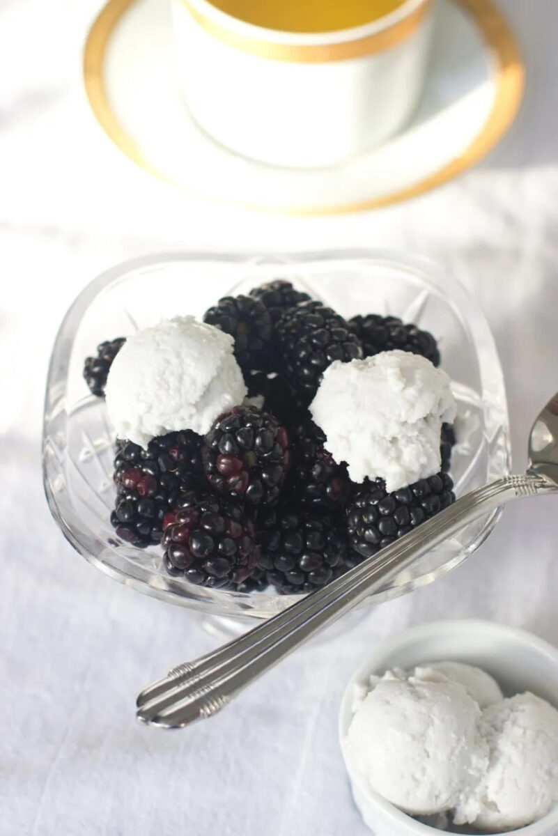 blackberries with coconut whipped cream in a glass with spoon