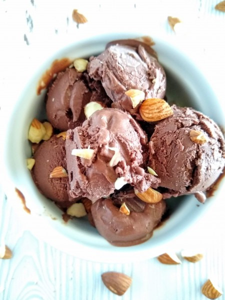 overhead shot of chocolate ice cream with sliced almonds  in a white bowl 