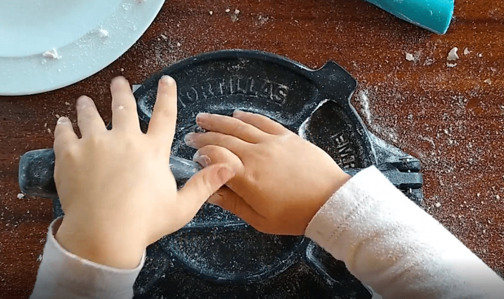 Five year old using tortilla press.