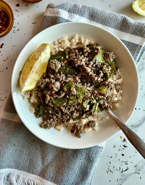 cooked ground meat with grape leaves served over rice in a white plate