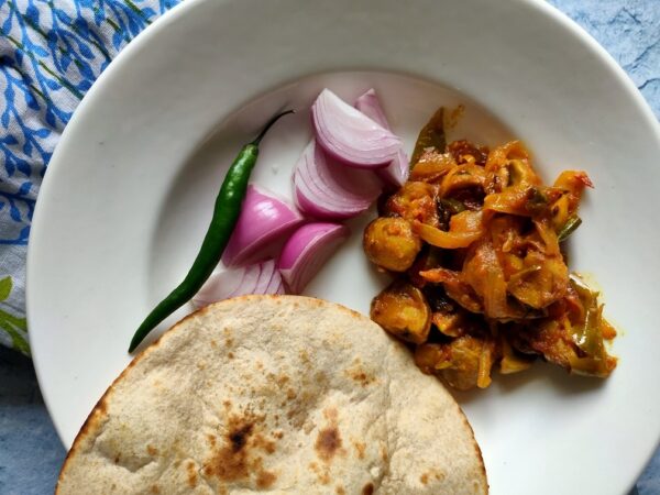 mushroom masala with slices of onions, jalapeno and bread on a white plate