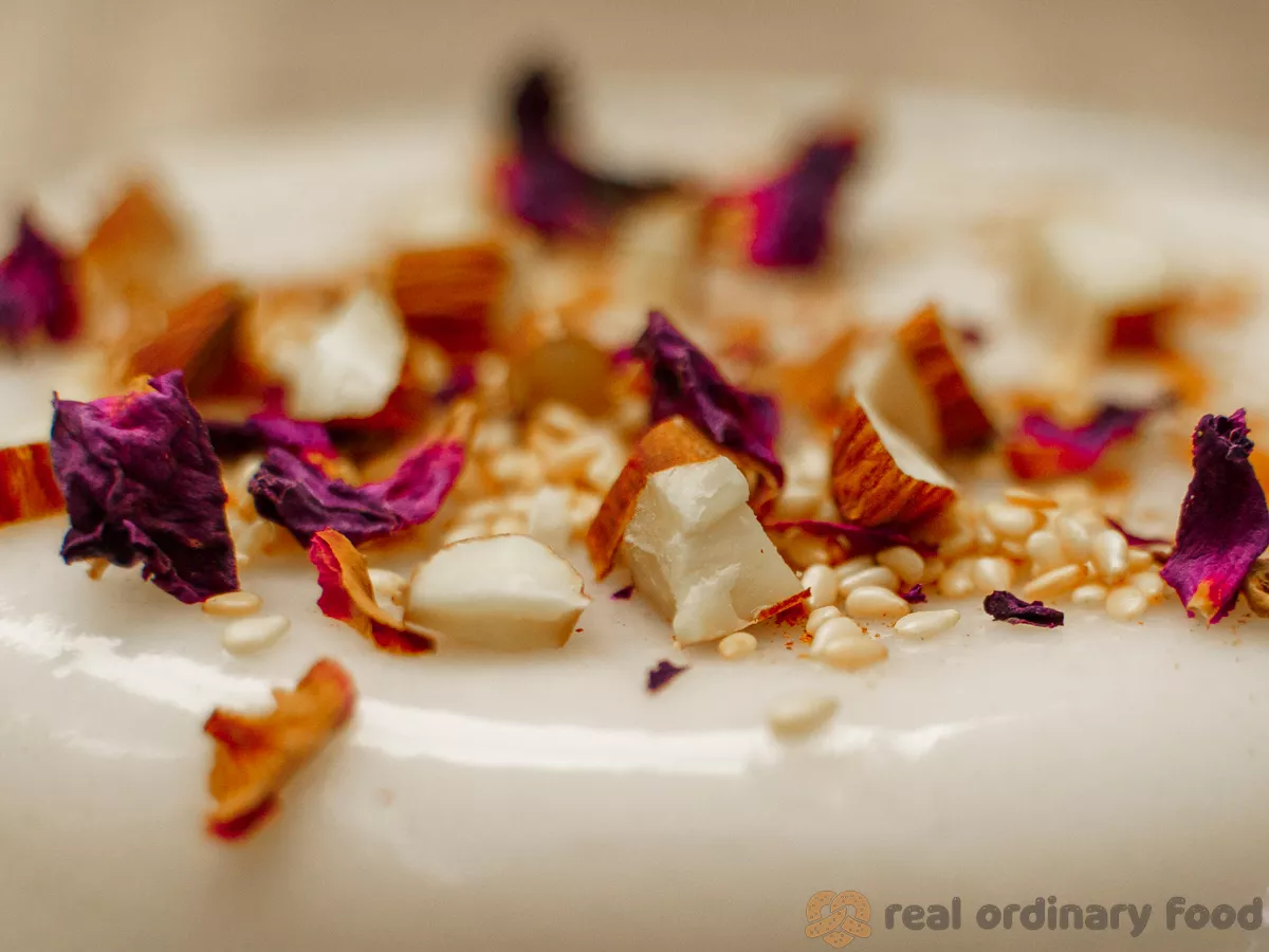 milky white pudding topped with rose petals and sliced almond nuts