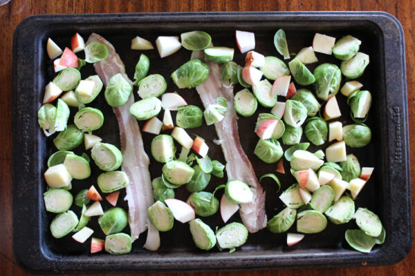 Apple bacon brussels sprouts on baking sheet ready to go in the oven.