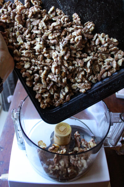 roasted walnuts being put on a food processor