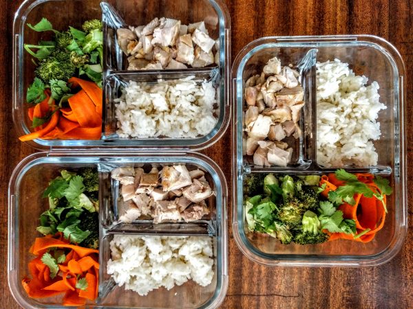 Chicken, broccoli, carrot noodles and rice meal prep peanut sauce containers.