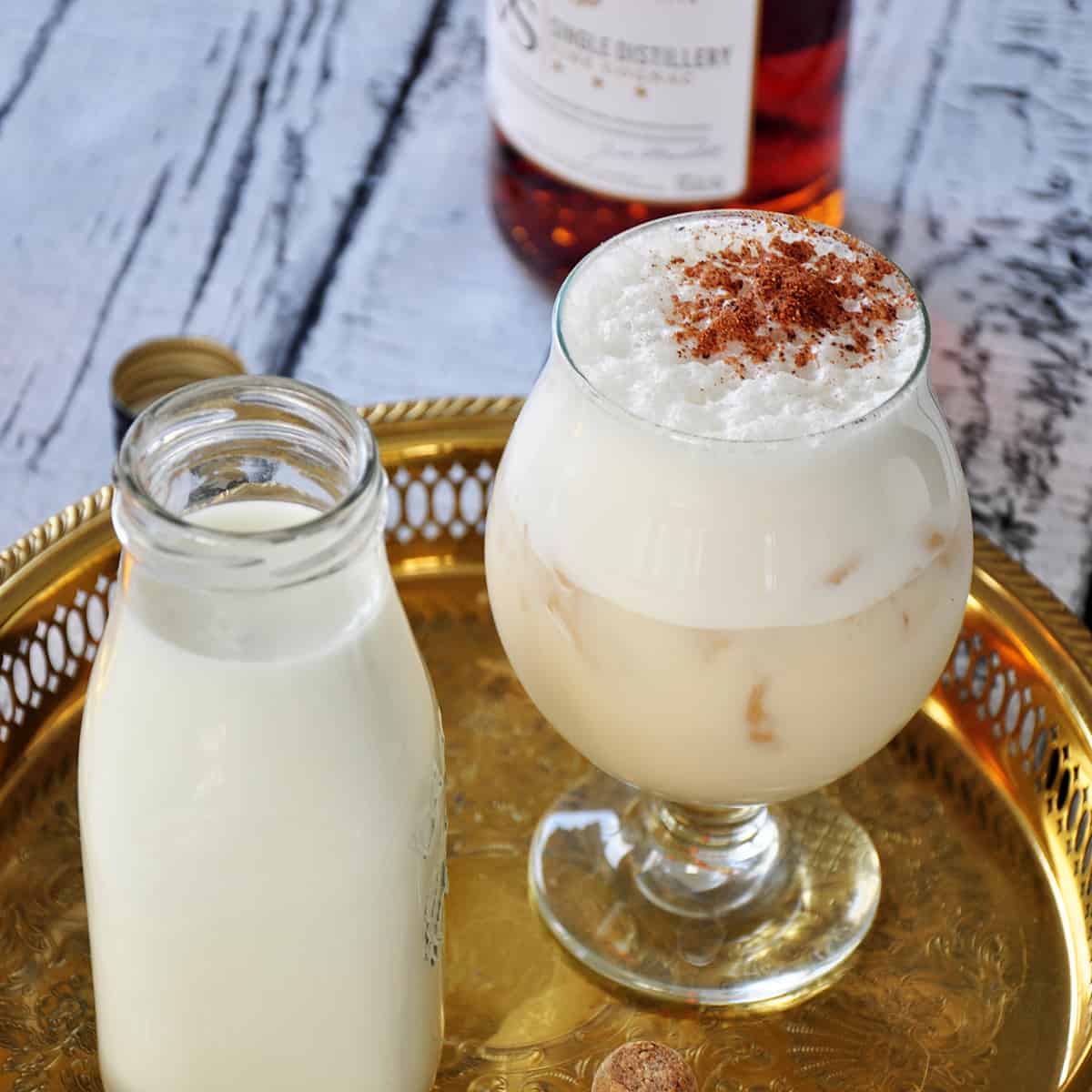 Christmas milk punch topped with cinnamon on golden serving tray