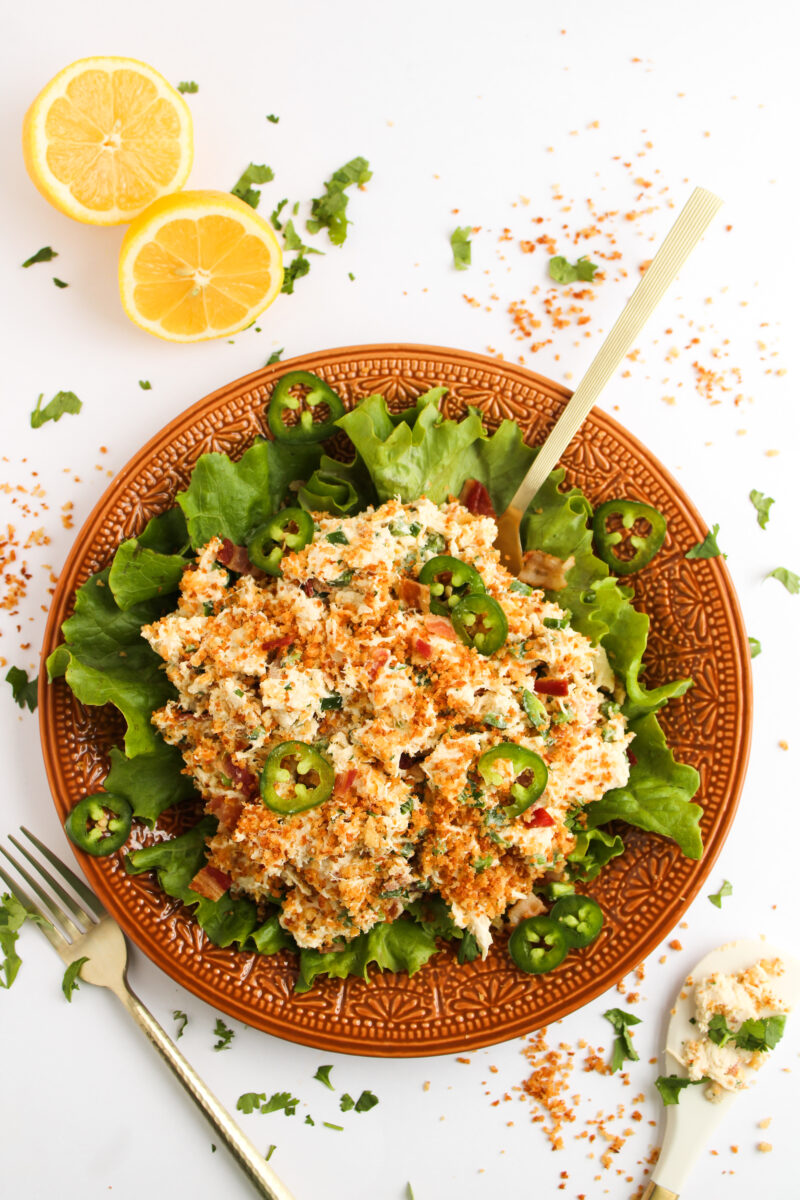Chicken salad on an orange plate with breadcrumbs sprinkled around.