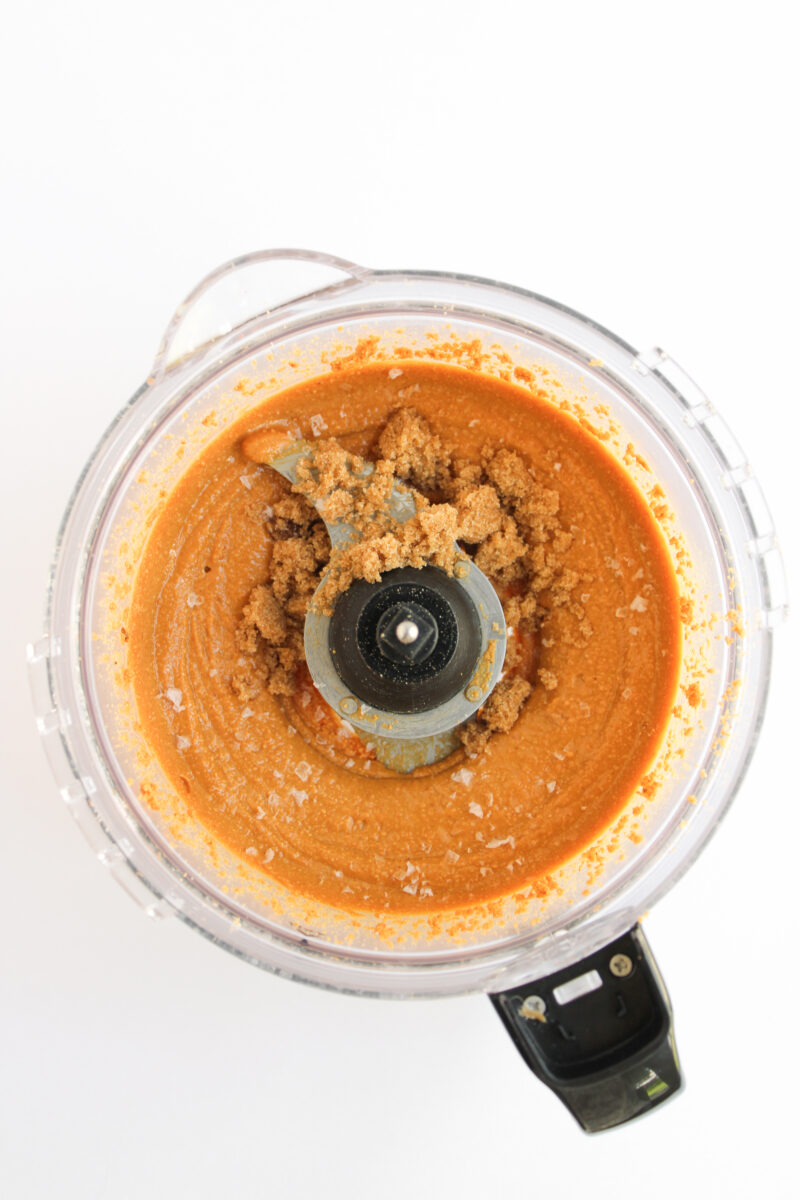 Peanut butter with brown sugar and salt in food processor on white background.