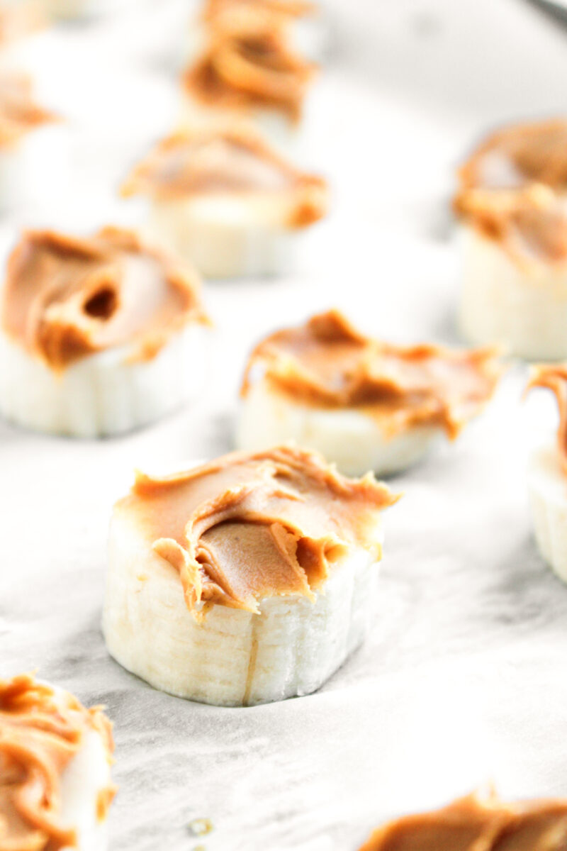Peanut butter spread on banana slice on parchment paper