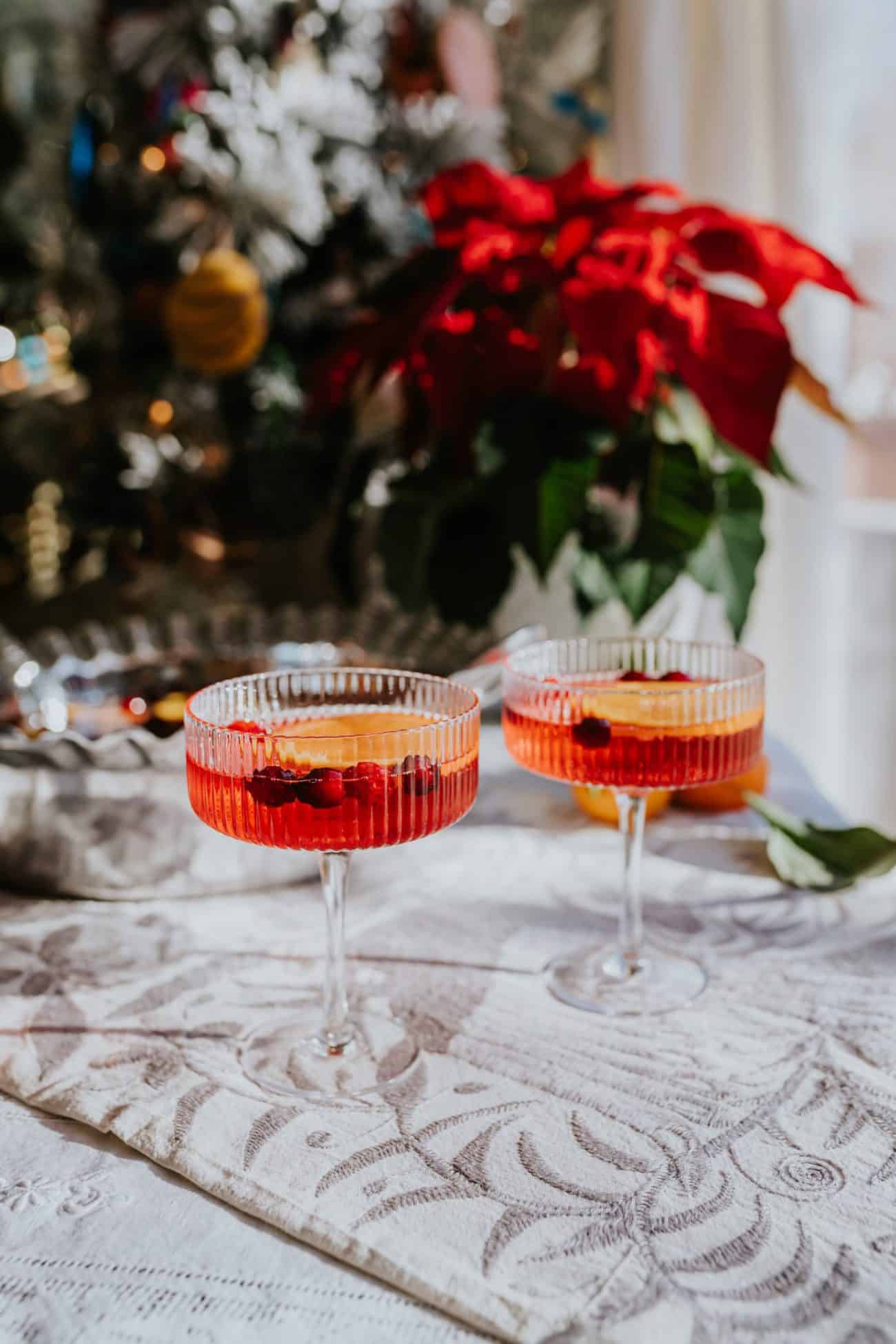 poinsettia punch with cranberries in cocktail glasses, festive poinsettia decorations on the background