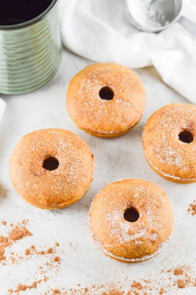 baked pumpkin doughnuts sprinkled with cinnamon and white sugar on white table 