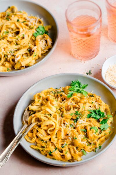 cooked pasta with pumpkin sauce topped with herbs on a white plate