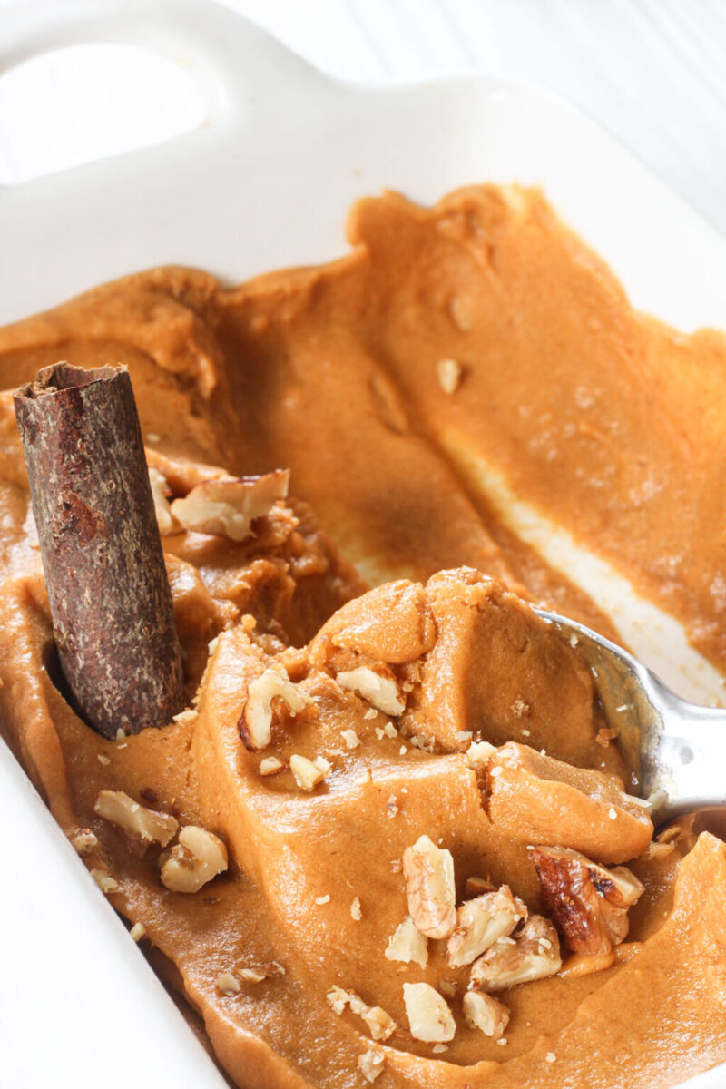 close up image of pumpkin spice banana nice cream topped with candied walnuts and cinnamon bark