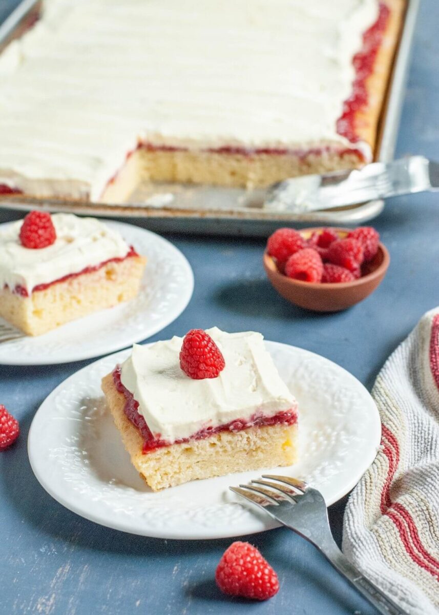 sliced raspberry vanilla sheet cake  on small white plates topped with raspberries