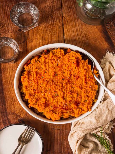 cooked shepherd's pie made with ground beef and vegetable casserole topped with mashed sweet potatoes in a serving dish