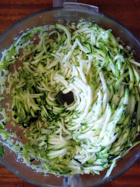 shredded zucchini in food processor bowl.