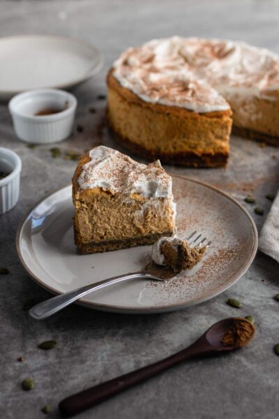 a slice of pumpkin cheesecake on a white saucer plate with a fork