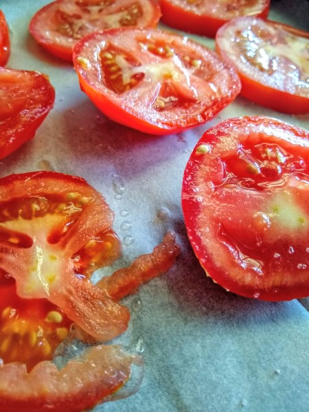 big tomato, sliced, on parchment lined baking sheet