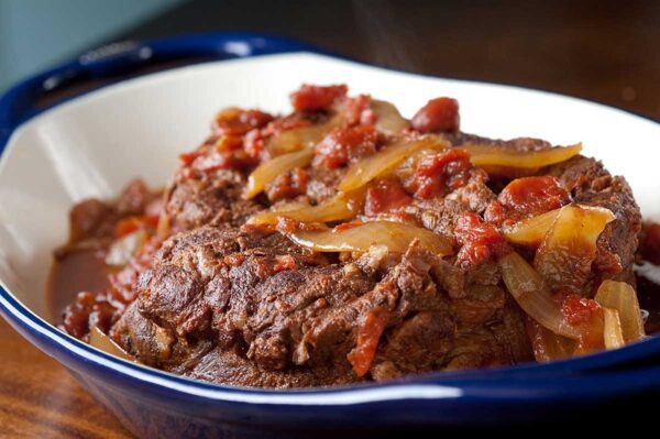 cooked beef, chipotle, onions, cumin and tomatoes in a serving blue white plate