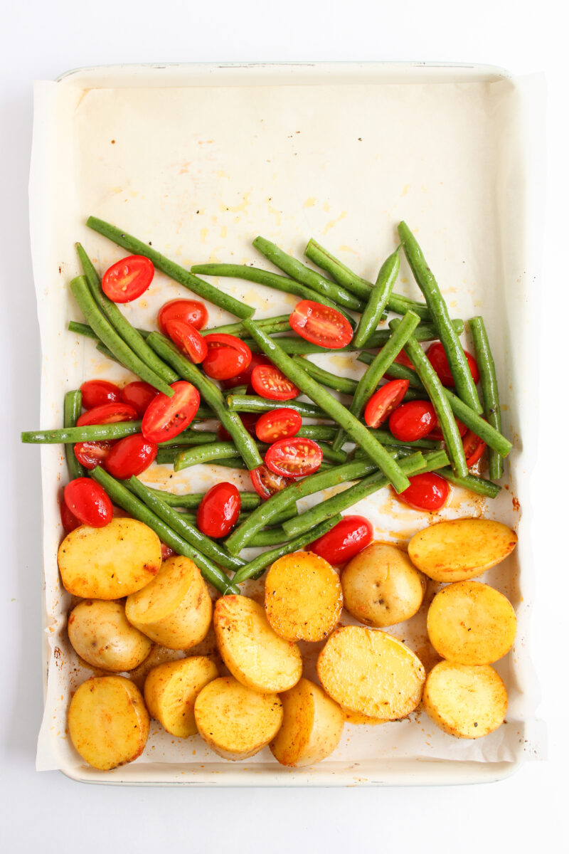 Vegetables arranged above potatoes on baking sheet