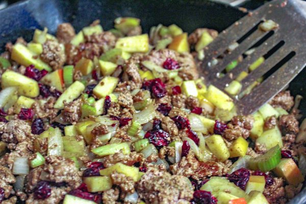 Stuffing ingredients - ground pork, onions, celery, apple and cranberries in the cast iron.