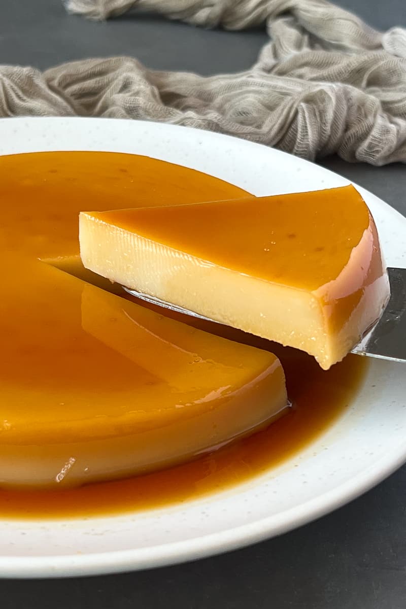 vegan flan being slice with knife on a white plate