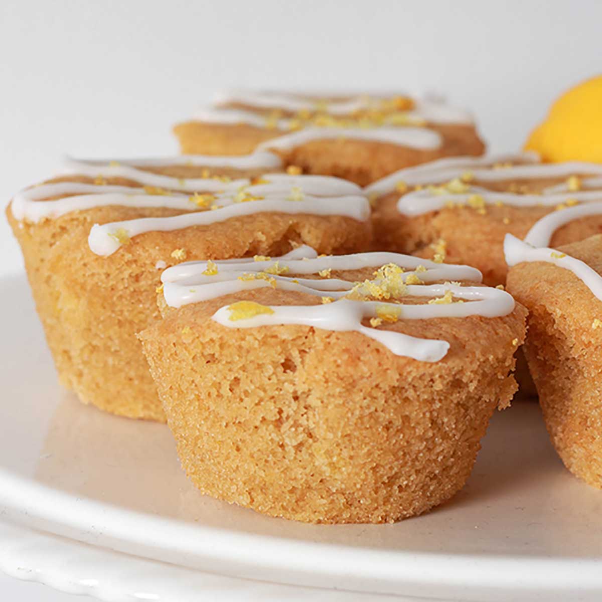 vegan lemon muffins with icing topped with grated lemon zest