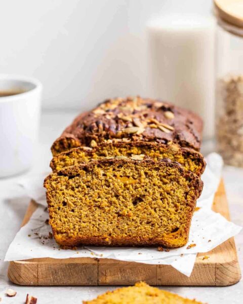 close up image of baked pumpkin banana bread loaf on a wood board