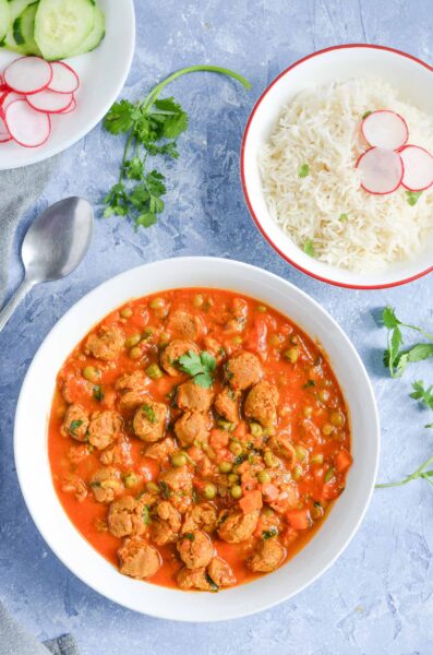 Veggie curry in a bowl and rice in a bowl on a table