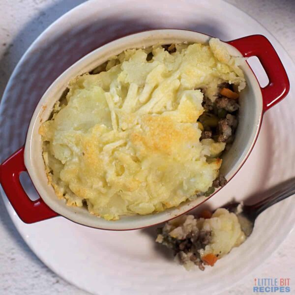 cooked shepherd's pie topped with cheese in a red baking dish